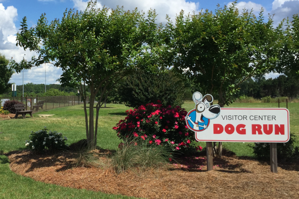 Visitor Center Dog Run sign with trees and flowers adjacent to interstate 95