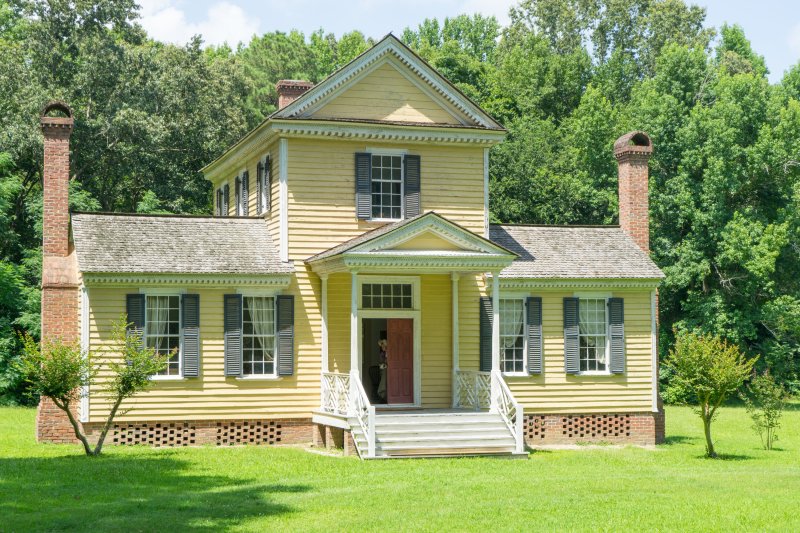 photo of historic home, yellow with black shutters.